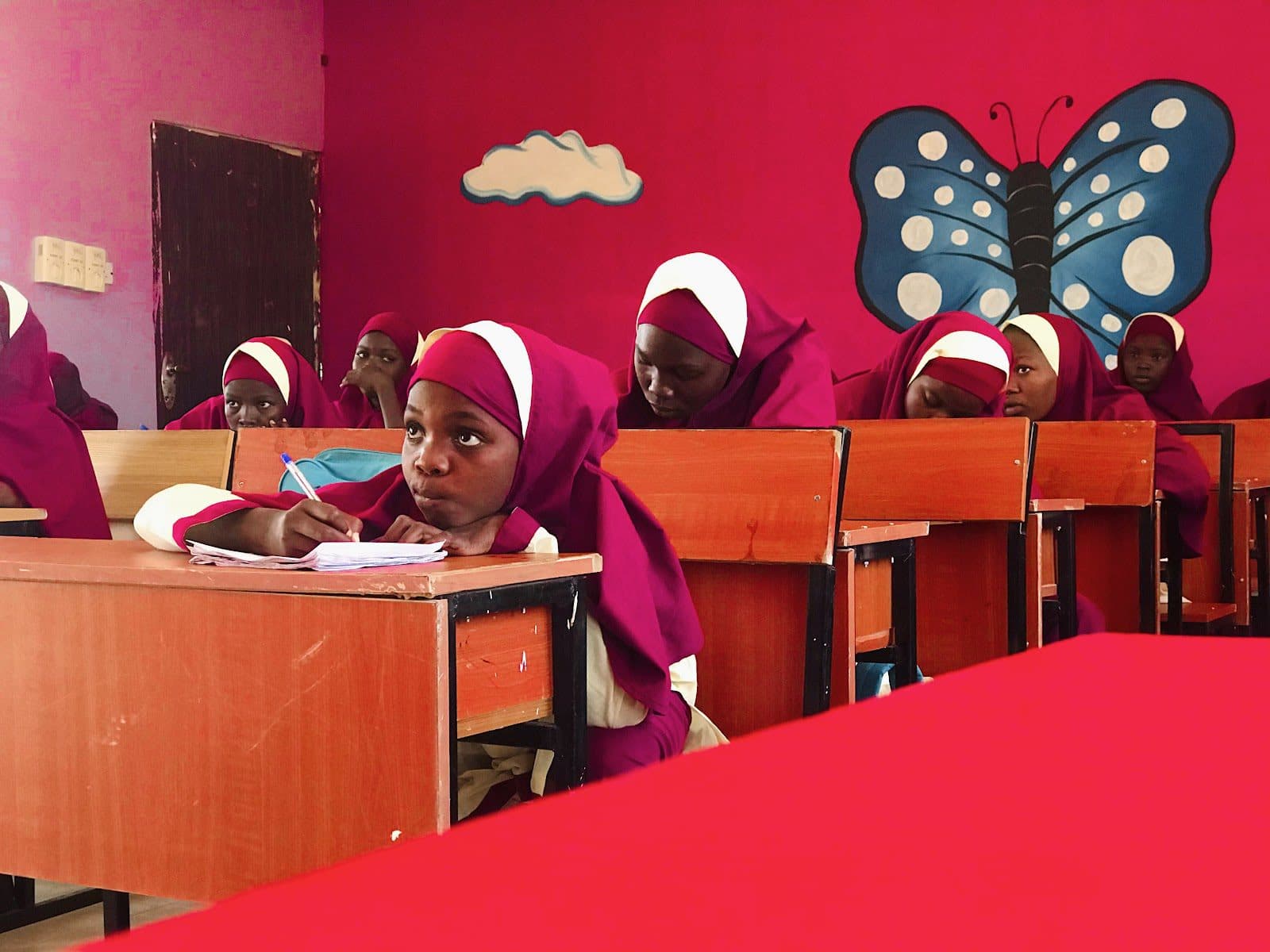 A group of girls sitting at desks in a classroom.