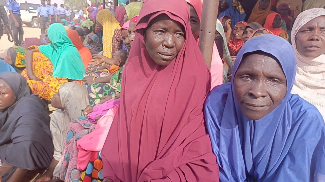 A group of women in colorful attire sitting outside during a daytime gathering.