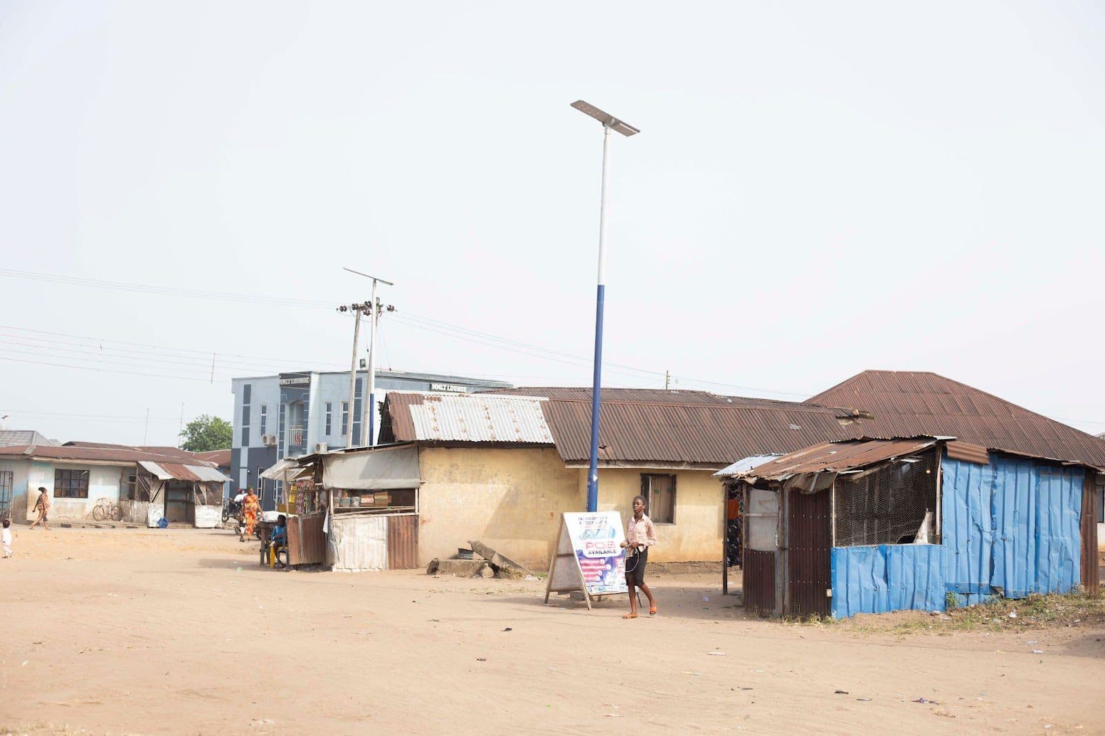 Rural street scene with traditional houses, a modern streetlight, and a person walking.