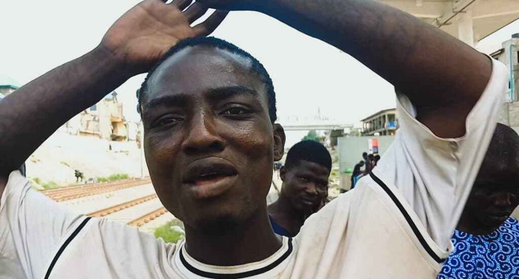 Man with hands on head looking puzzled or stressed with onlookers in the background.