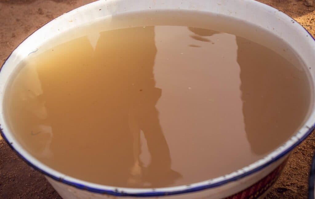 A large basin filled with murky brown water, reflecting a vague silhouette.