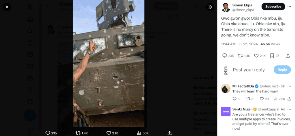 A person showing a peace sign through the shattered window of a bullet-riddled armored vehicle.