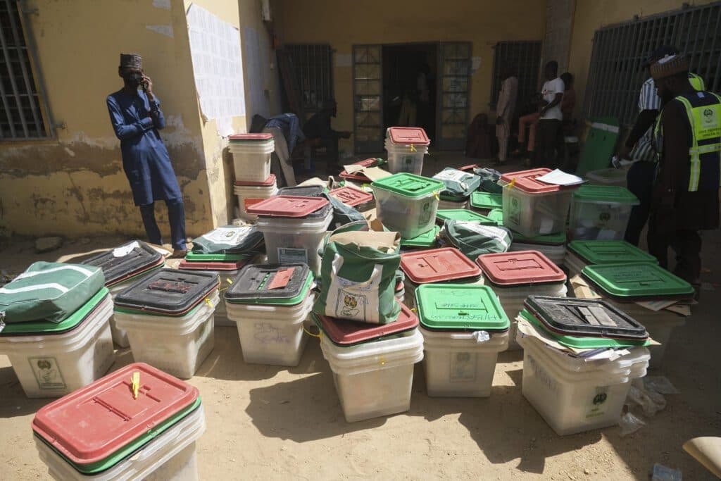 Election officials and stacked ballot boxes at a polling station.