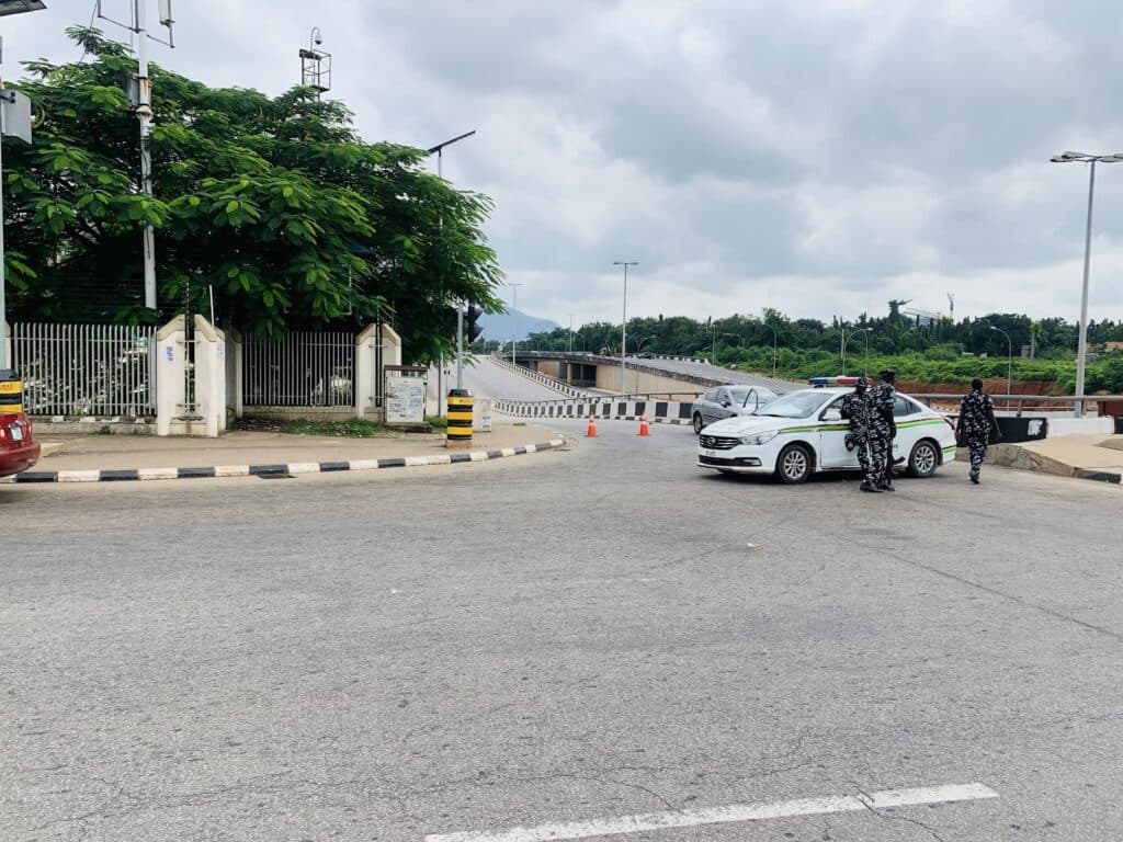 Security checkpoint with uniformed officers inspecting a car on a road.