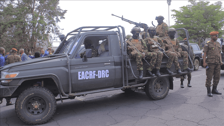 A military vehicle with soldiers onboard and others standing beside, labeled "EACRF-DRC."