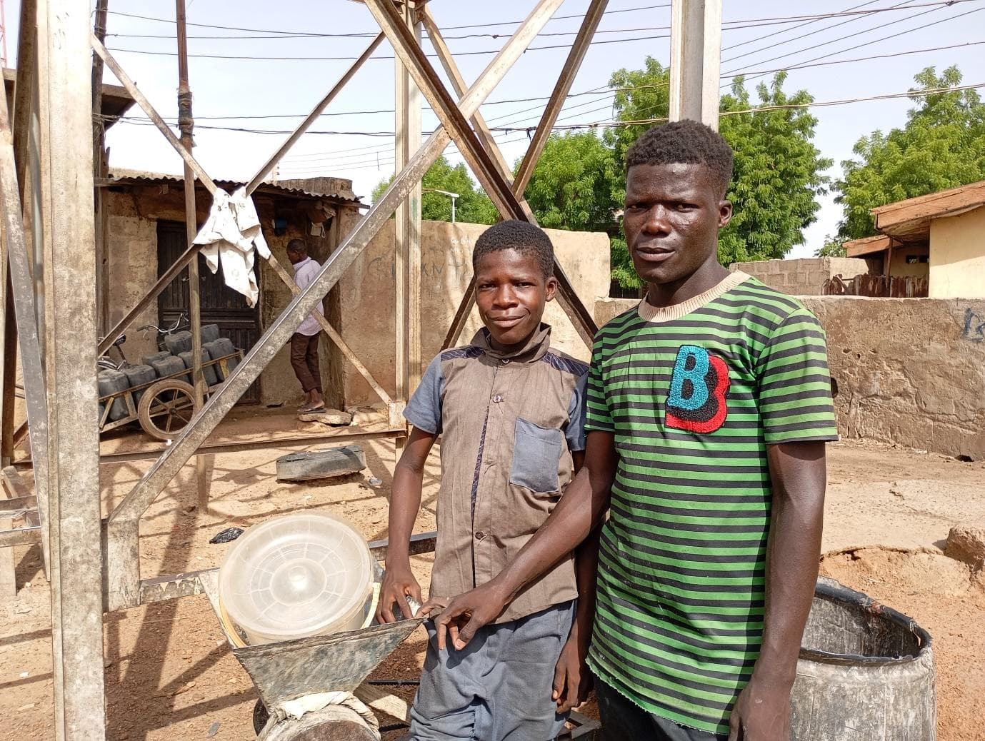 Ibrahim and Isma’il pose for a picture at their place of labour with their disc mill grinder at Kuka, Tsohuwar Kasuwa, Potiskum.