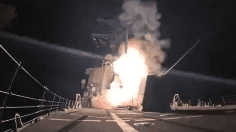 Ship launching a missile at night with flames and smoke visible against the dark sky.