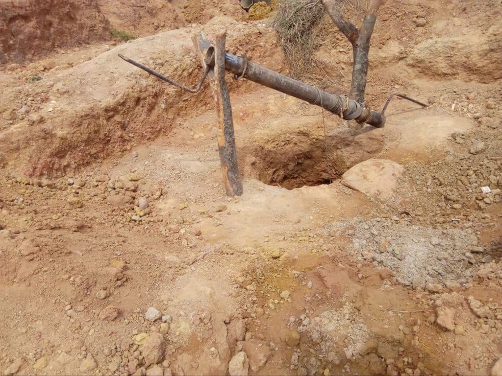 A makeshift lever device is set up on a dry, rocky field, possibly for digging or excavation purposes.