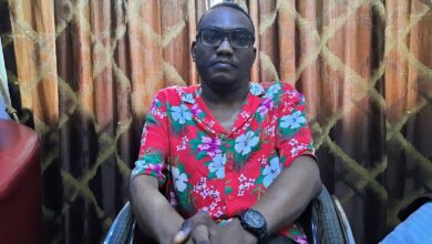 Ibrahim wears a flowery red t-shirt and sits on a wheelchair in a hotel room in Ikeja, Lagos, as he grants the interview. He is wearing glasses and a black analog watch and rests both hands on his knees.
