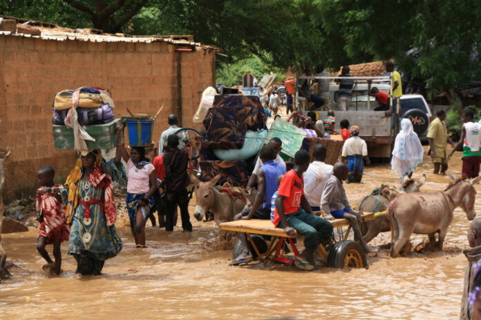 people using donkey carts to cross a flooded river