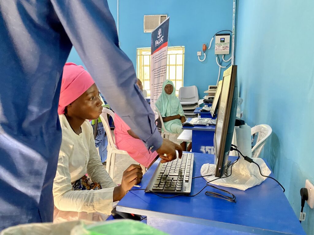 A schoolgirl in Northeast Nigeria look on as she's instructed on how to use a computer.
