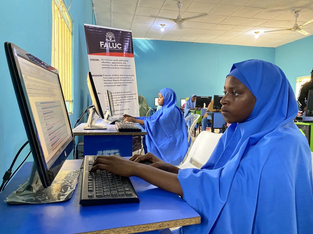 A young schoolgirl in the Northeast of Nigeria sits in front of a computer as she writes her JAMB exam.