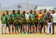 Coordinators of Music Plus Football pose with players from one of the teams on a community football pitch.