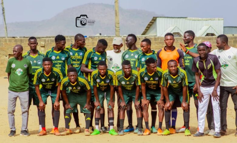 Coordinators of Music Plus Football pose with players from one of the teams on a community football pitch.