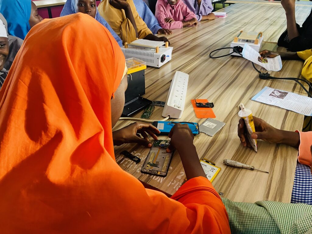 A group of women working on electronics at a table.