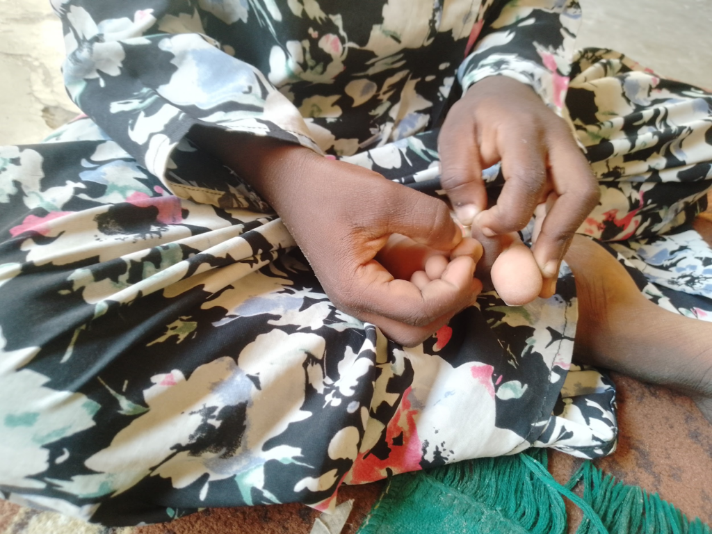 Person in a floral dress holding two small eggs in their hands, sitting on the floor.