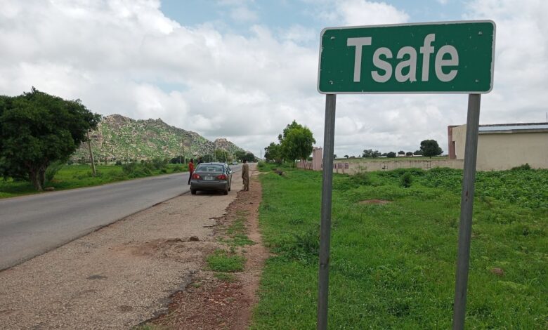 Green road sign reading "Tsafe" by a roadside with cars and lush greenery.