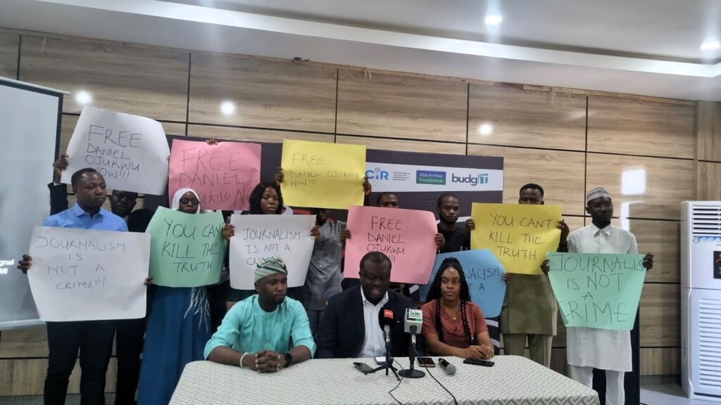 Group of people holding protest signs advocating for the freedom of Daniel Otukwu and stating that journalism is not a crime.