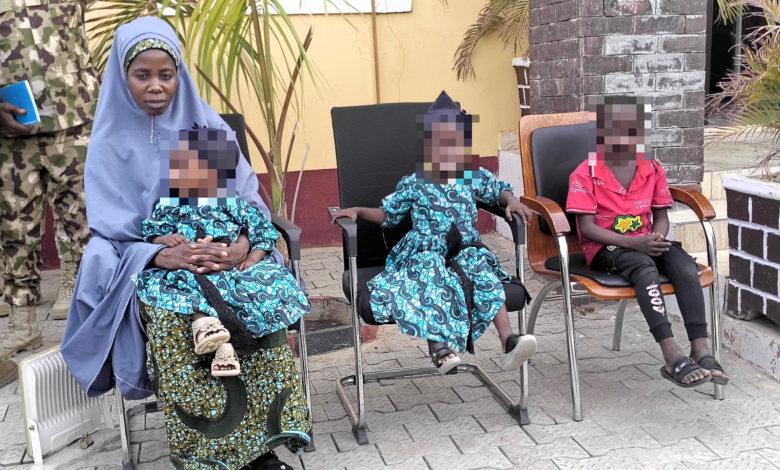 Woman in blue hijab sitting next to children in matching outfits, faces pixelated for privacy.