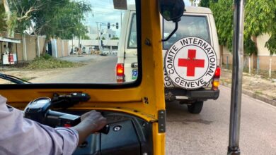 View from inside an auto rickshaw looking at a Red Cross vehicle on the road.