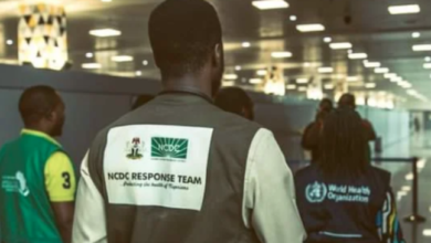 Person wearing a "NCDC RESPONSE TEAM" vest at an airport with others in the background.