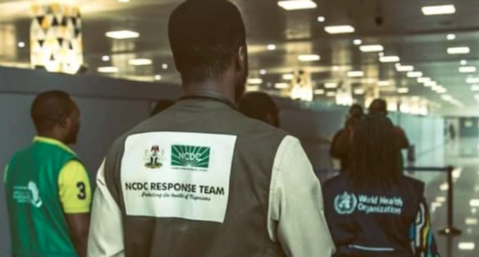 Person wearing a "NCDC RESPONSE TEAM" vest at an airport with others in the background.