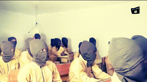 Students in a classroom with heads covered by cloth, sitting at wooden desks.