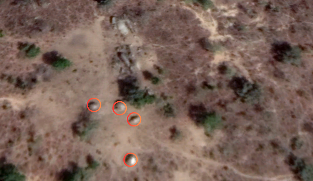 Aerial view of a dry landscape with sparse vegetation and three red circles highlighting specific areas.