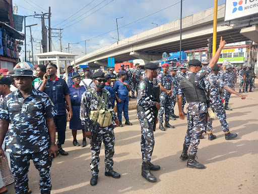 A group of police officers in camouflage uniforms gathered on a busy street with some directing traffic.