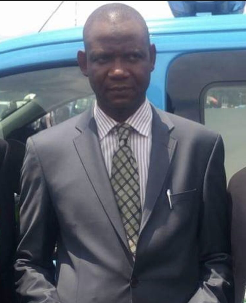 Man in suit standing in front of blue vehicle.