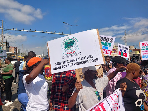 Protesters holding signs, one reads "STOP STEALING PALLIATIVES MEANT FOR THE WORKING POOR."