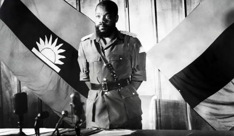 A man in military attire stands between two flags with a sun emblem, in front of microphones, evoking a historical scene.