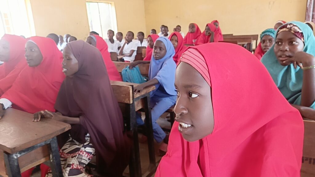 Classroom full of attentive students wearing colorful hijabs.