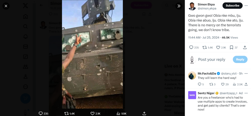 A person showing a peace sign through the shattered window of a bullet-riddled armored vehicle.