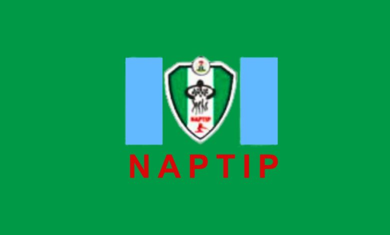 A green flag with a crest flanked by two blue vertical rectangles and the acronym "NAPTIP" in red at the bottom.