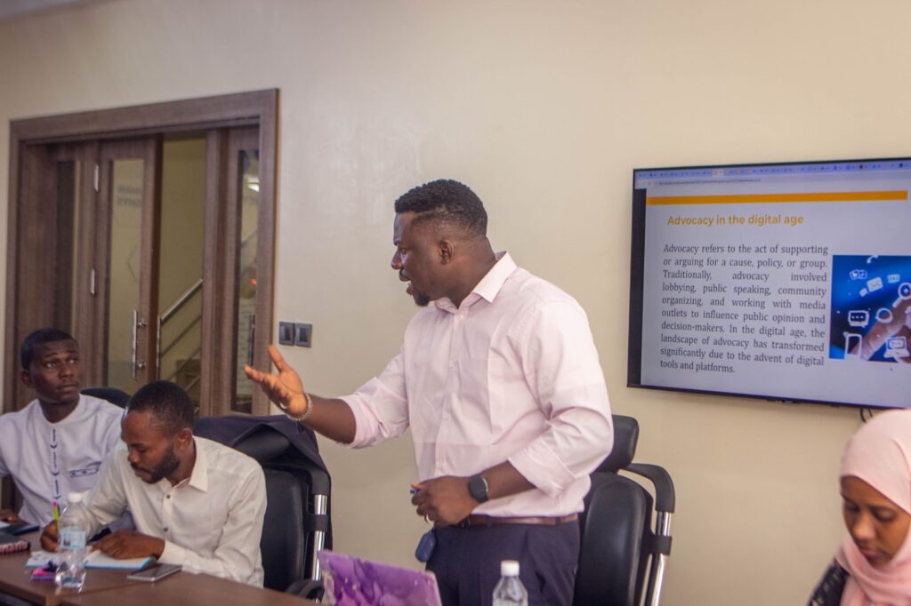 Man presenting at a workshop with a slide titled "Advocacy in the digital age" in the background.