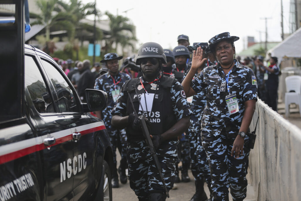 Nigerian security personnel in camo uniforms next to their vehicle during an event.