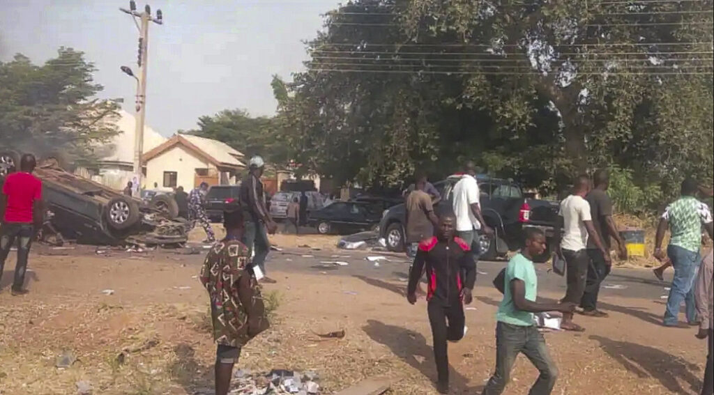 Car overturned in an accident on a street with bystanders and debris around.