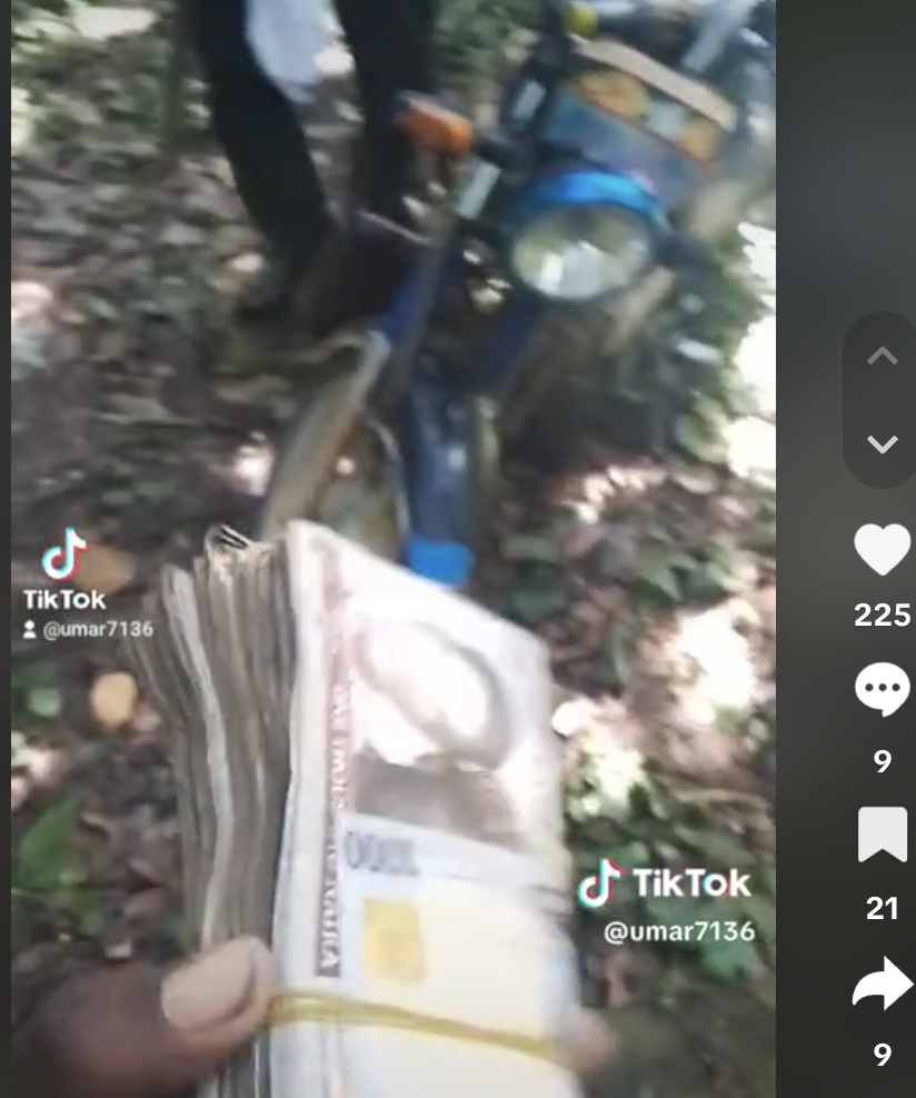 Hand holding cash with indistinct figures near a motorcycle in the background.