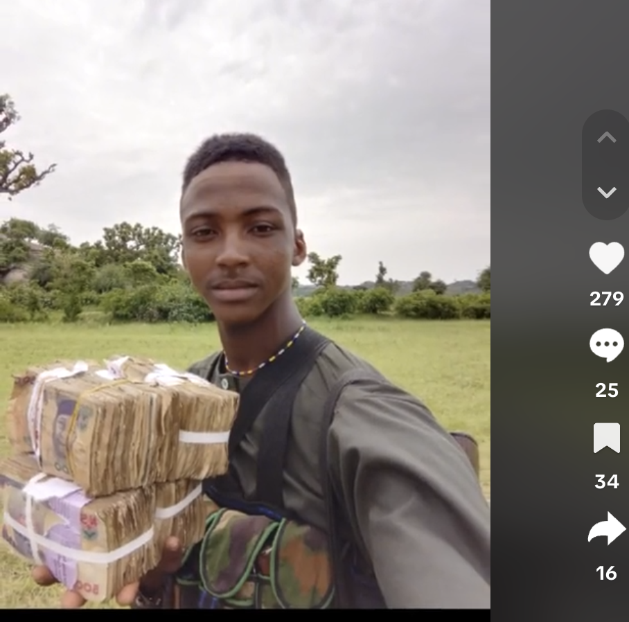 Man holding a large amount of bundled banknotes with a field in the background.