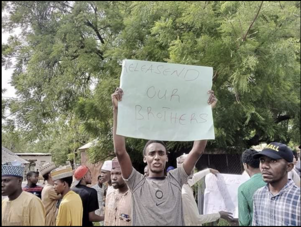 People protesting with signs, one reads "RELEASEND OUR BROTHERS."