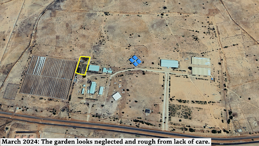 Aerial view of a sparse, dry landscape with scattered buildings and a neglected garden area surrounded by fencing.