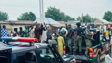 Law enforcement officers on vehicles in a busy street with onlookers.