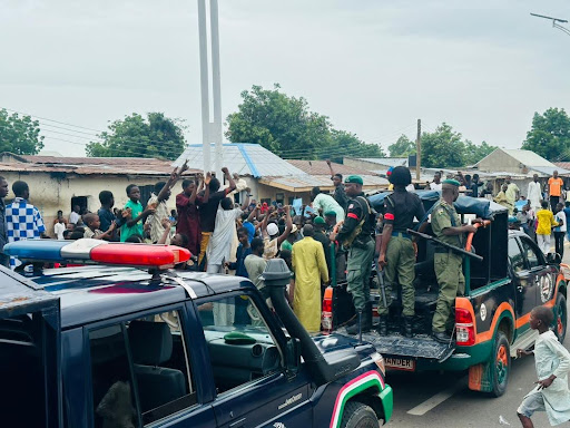 Law enforcement officers on vehicles in a busy street with onlookers.