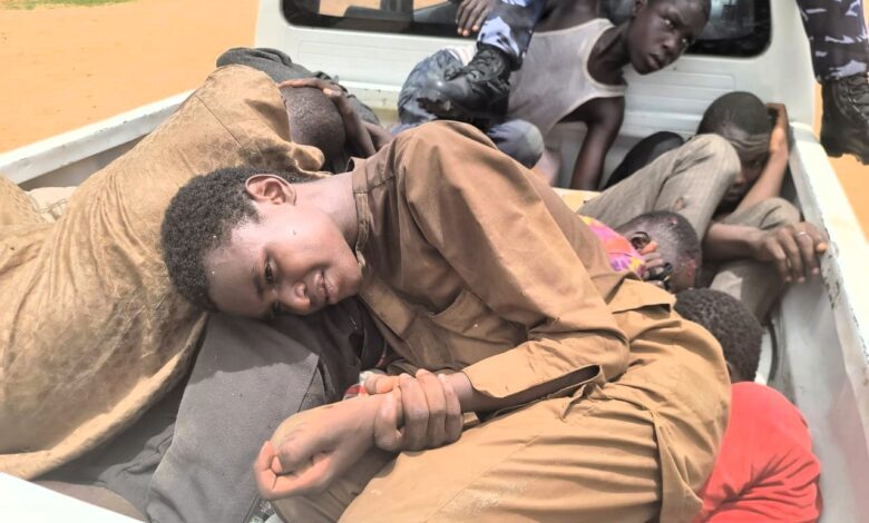 Several people lying in the back of a pickup truck, with a focus on one individual looking at the camera.