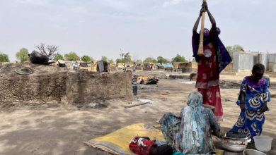 People amidst a makeshift environment with basic belongings, indicating a scene of daily life in a resource-scarce setting.