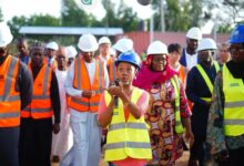 Group of people in safety gear with a woman speaking into a walkie-talkie.