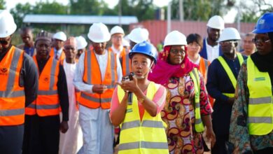 Group of people in safety gear with a woman speaking into a walkie-talkie.