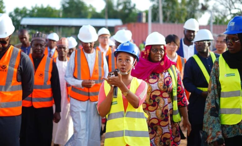 Group of people in safety gear with a woman speaking into a walkie-talkie.