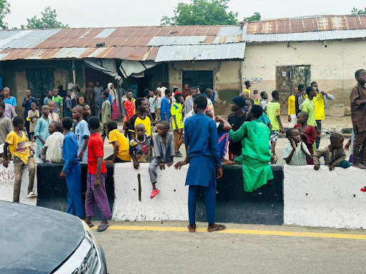 Group of people gathered on a street with buildings in the background.